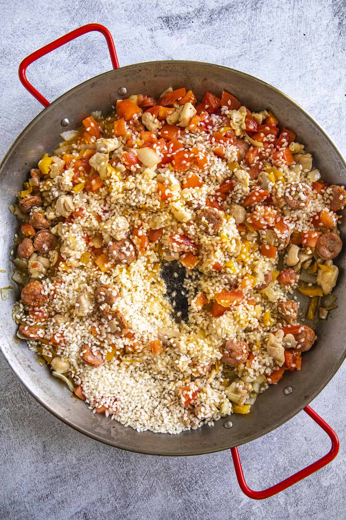 Adding Spanish rice to the paella pan