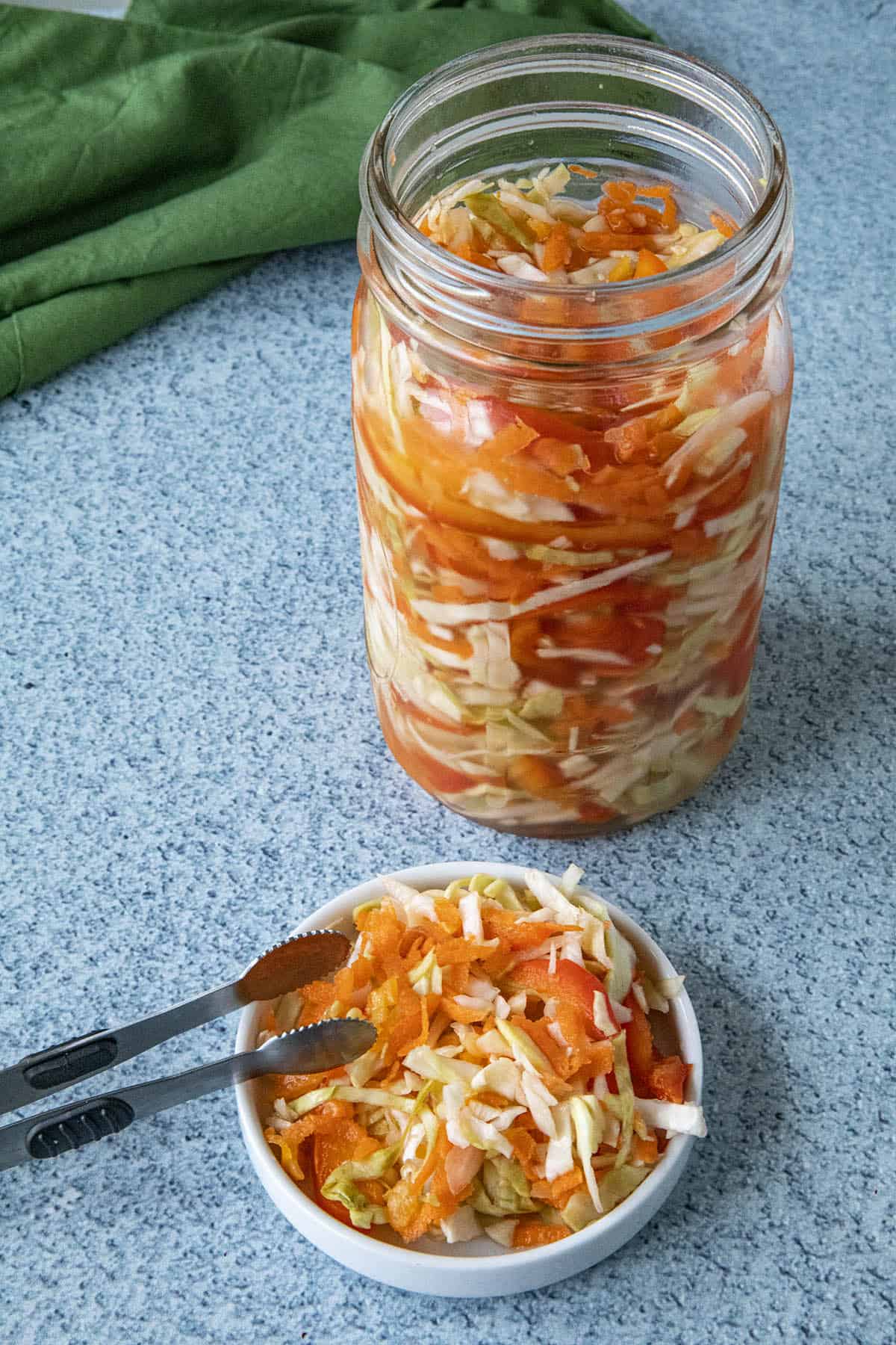 Pikliz in a bowl, ready to serve, with a jar of Pikliz behind it