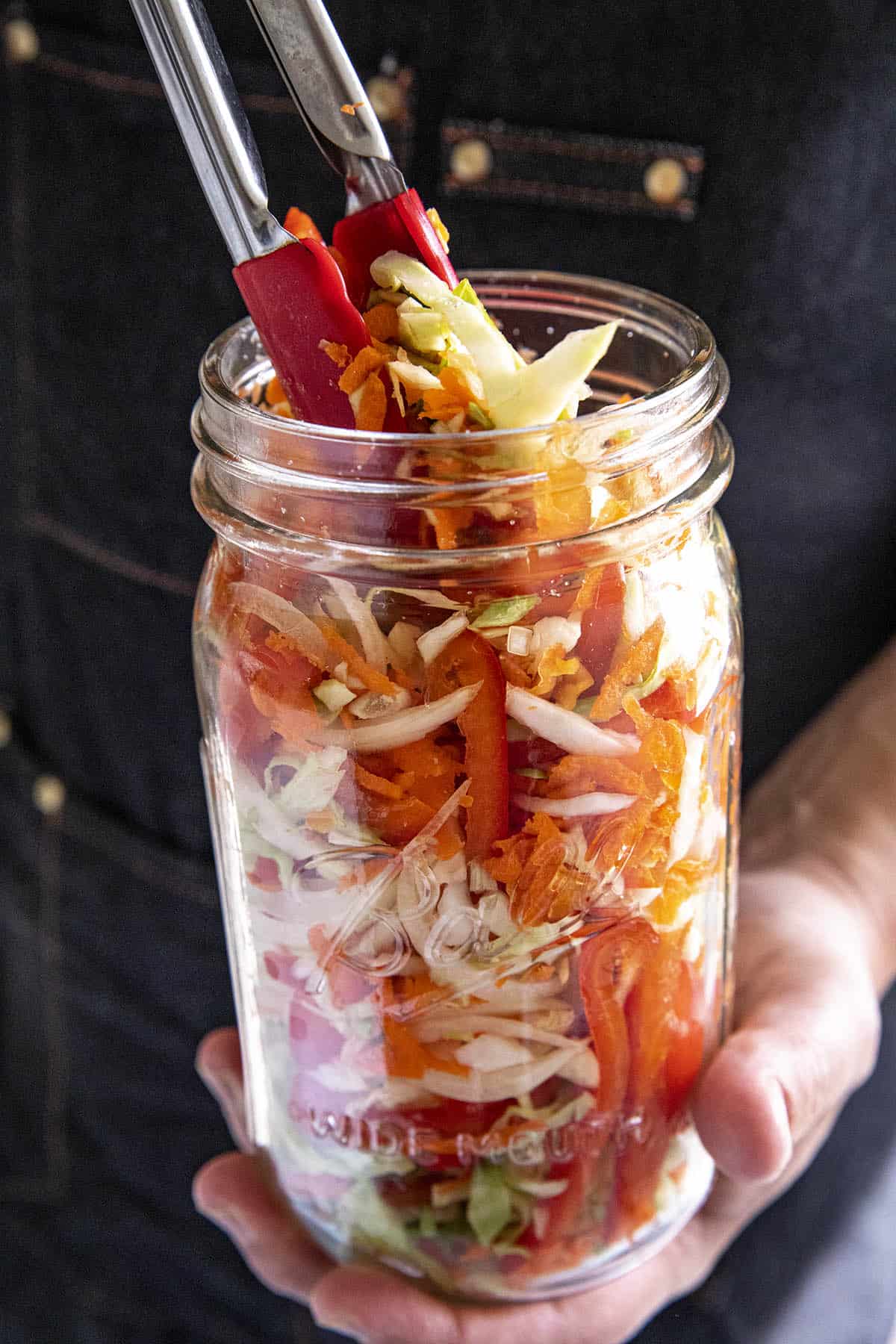 Stuffing the vegetables into the jar to make Pikliz