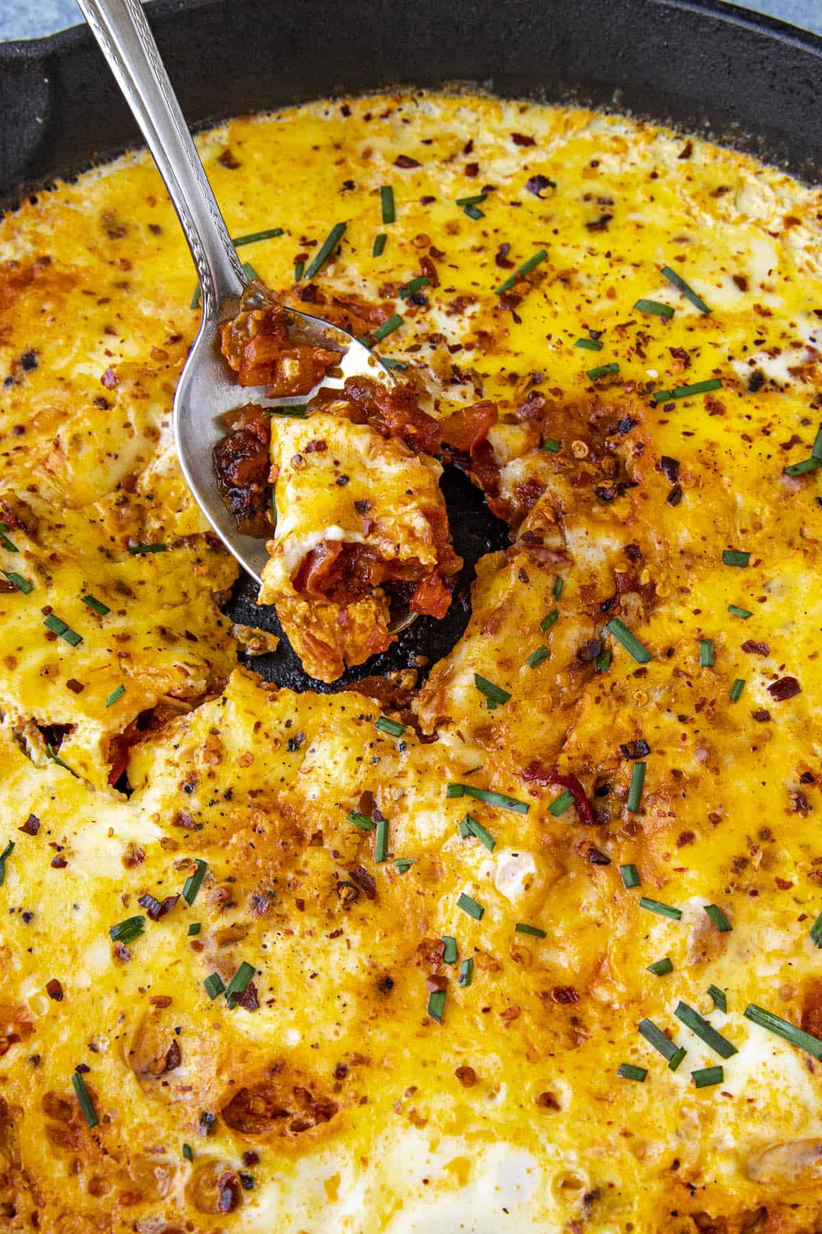 A scoop of Menemen being taken from the serving pan