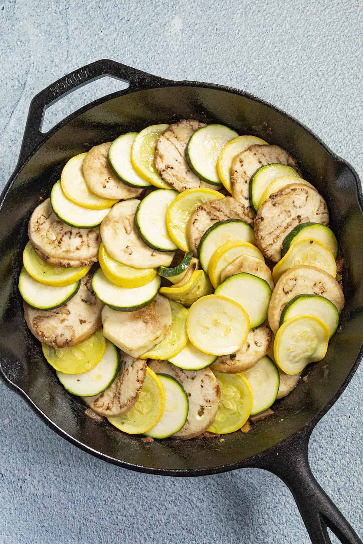 Layering on the sauteed vegetables over the tomato sauce in the pan