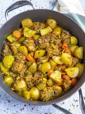 Jamaican Curry Chicken in a pan with garnish