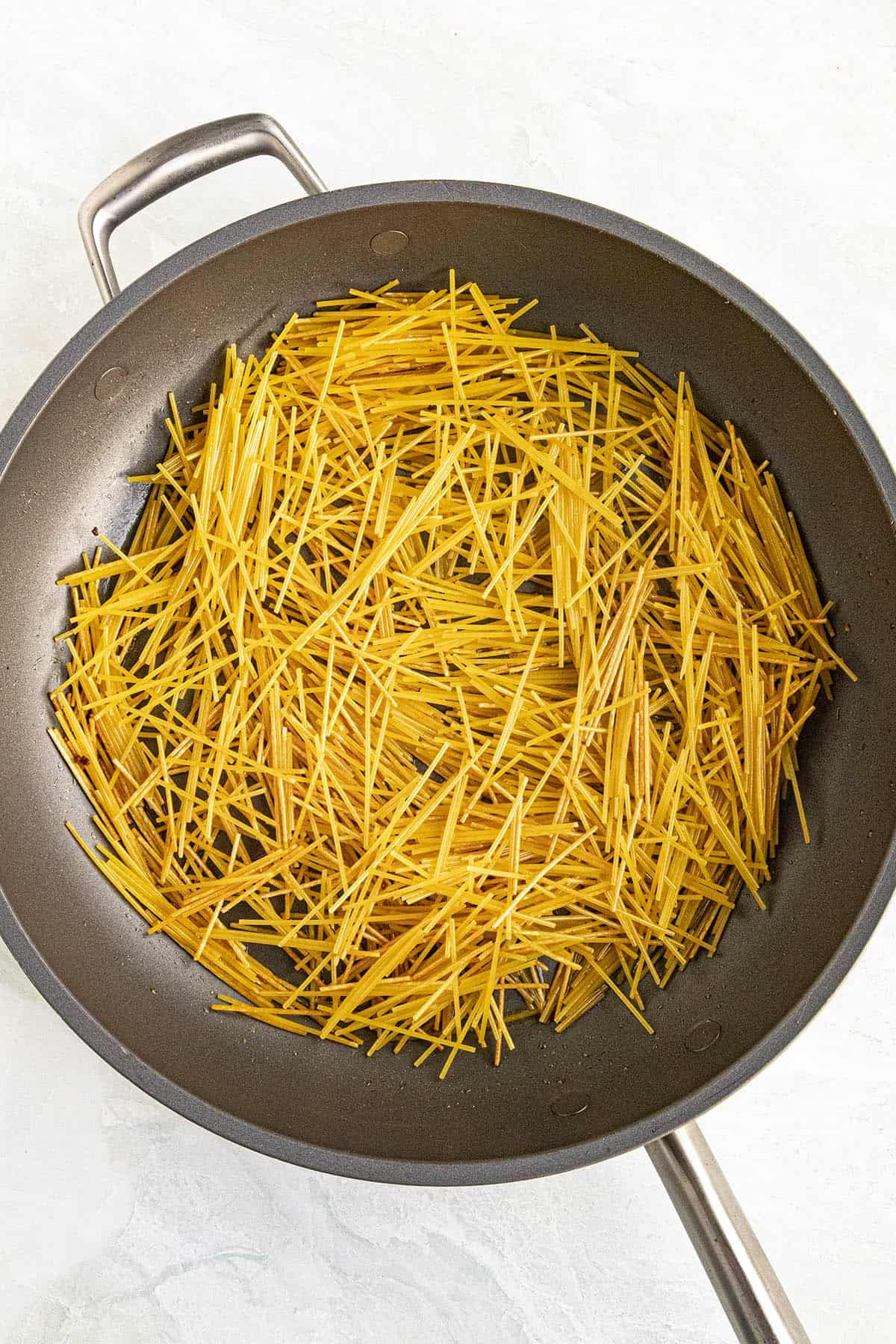 Browning fideo noodles in a pan to make Sopa de Fideo