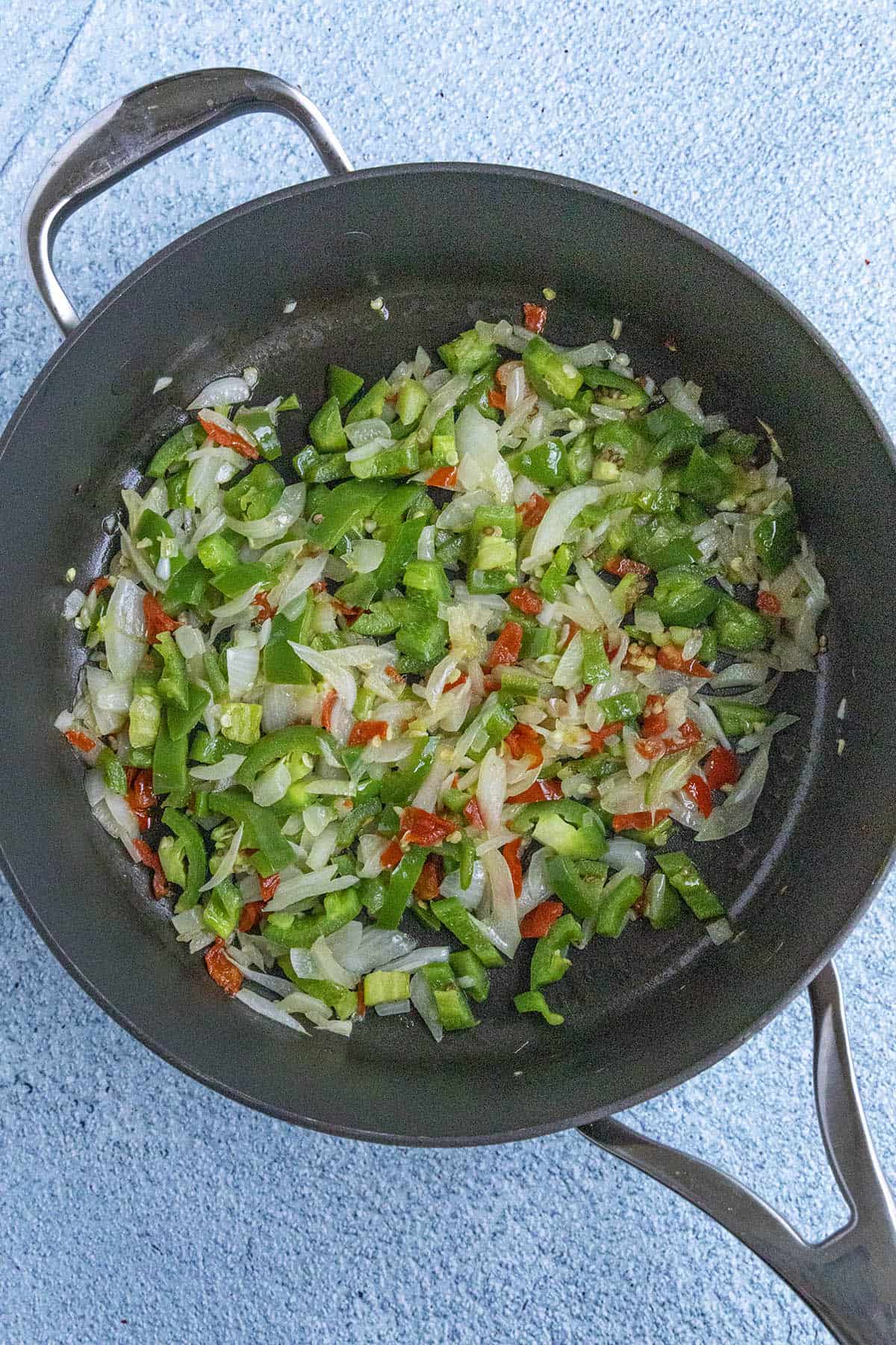 Cooking down onions and peppers to make Jamaican Curry Chicken