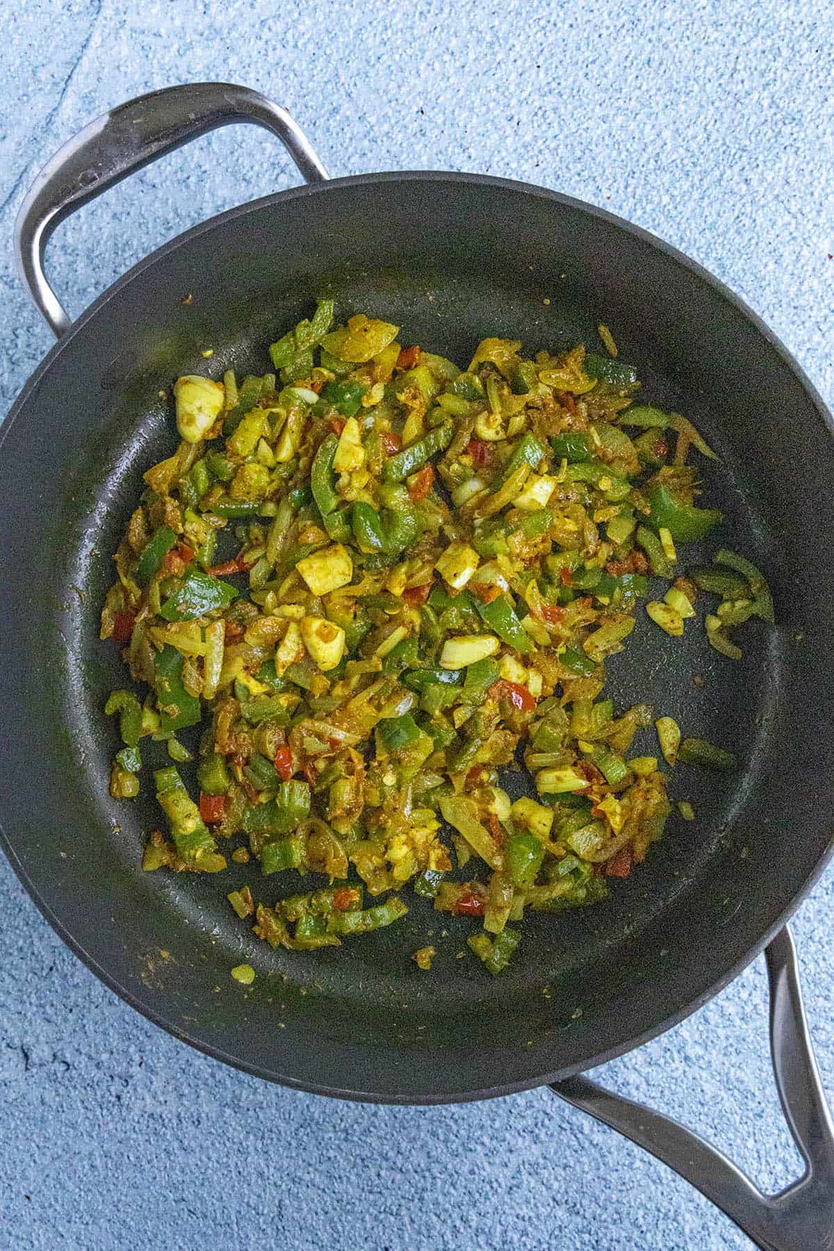 Cooking down vegetables and spices to make Jamaican Curry Chicken