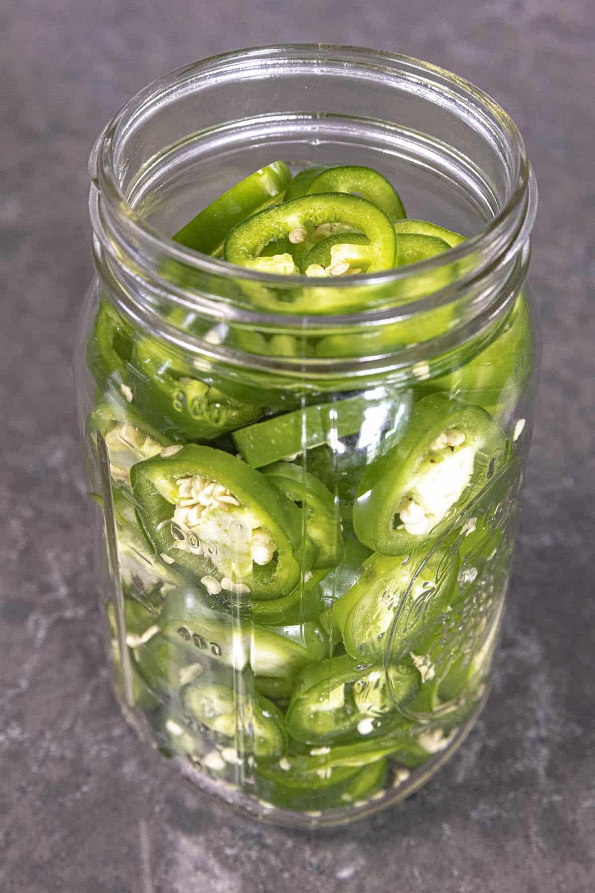 Jalapeno slices in a jar ready for pickling