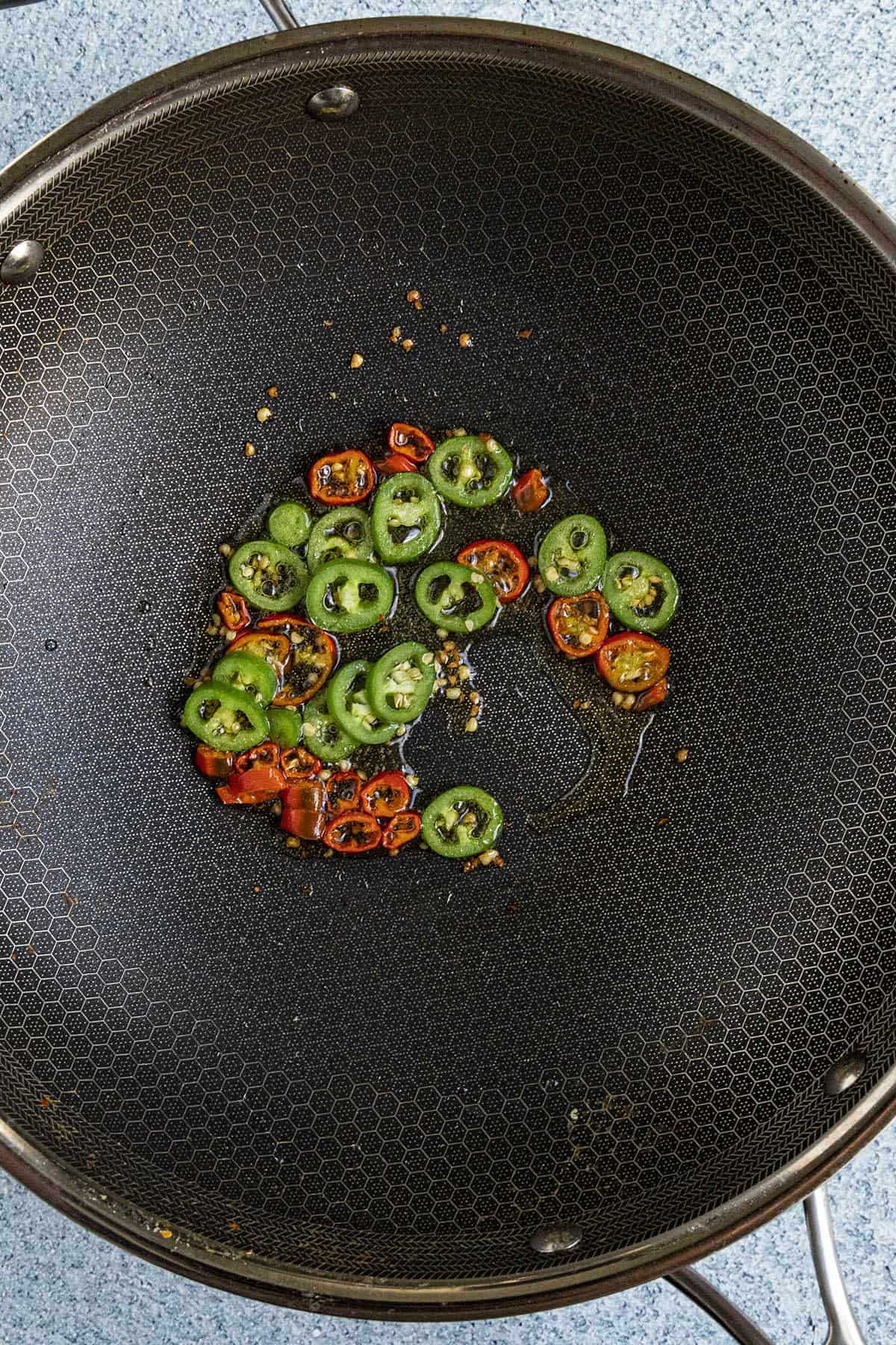Cooking spicy peppers in a hot pan to make Spicy Noodles