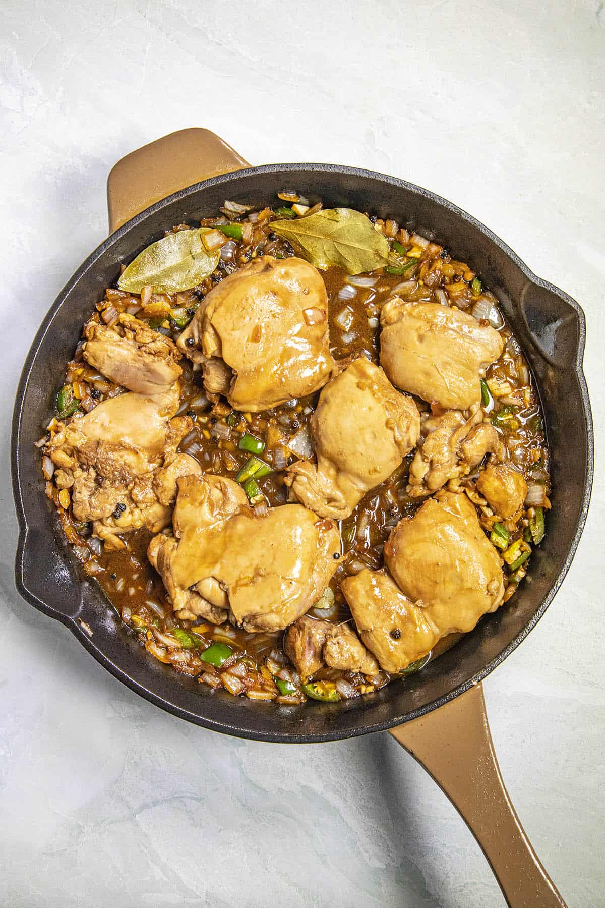Simmering Chicken Adobo in a pan with vegetables and adobo sauce