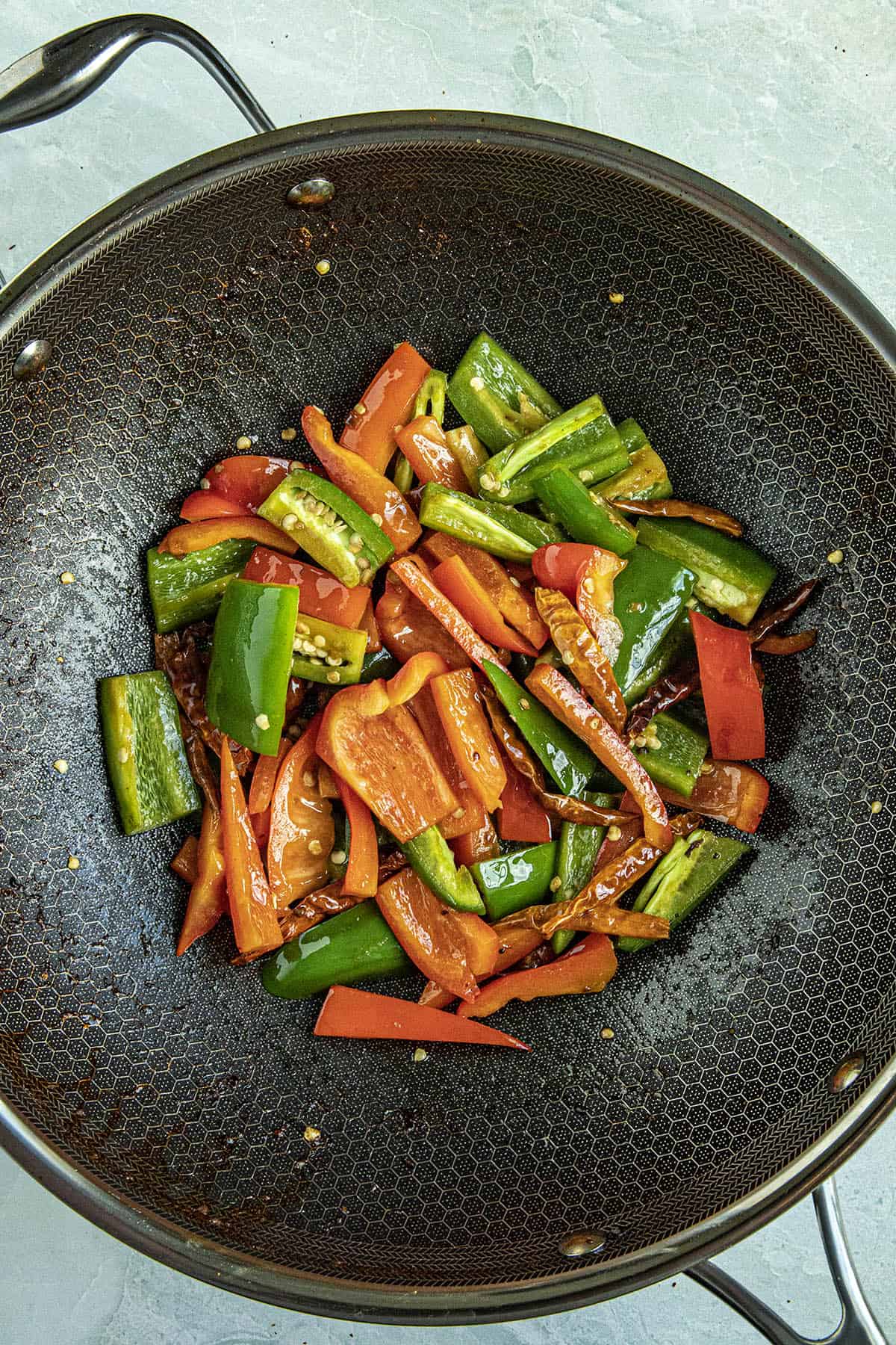 Stir frying peppers and vegetables to make Kung Pao Shrimp