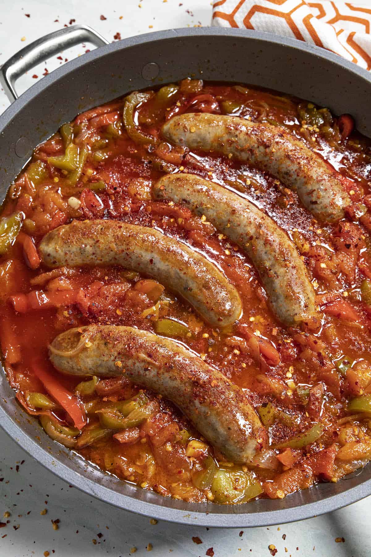 Spicy Piperade in a hot pan, simmering with sausages