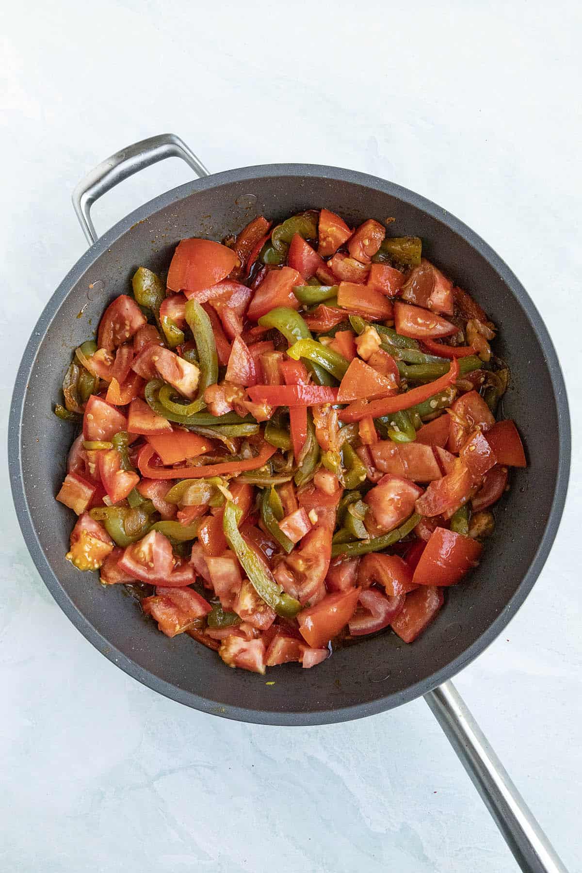 Tomatoes added to the pan to make Piperade