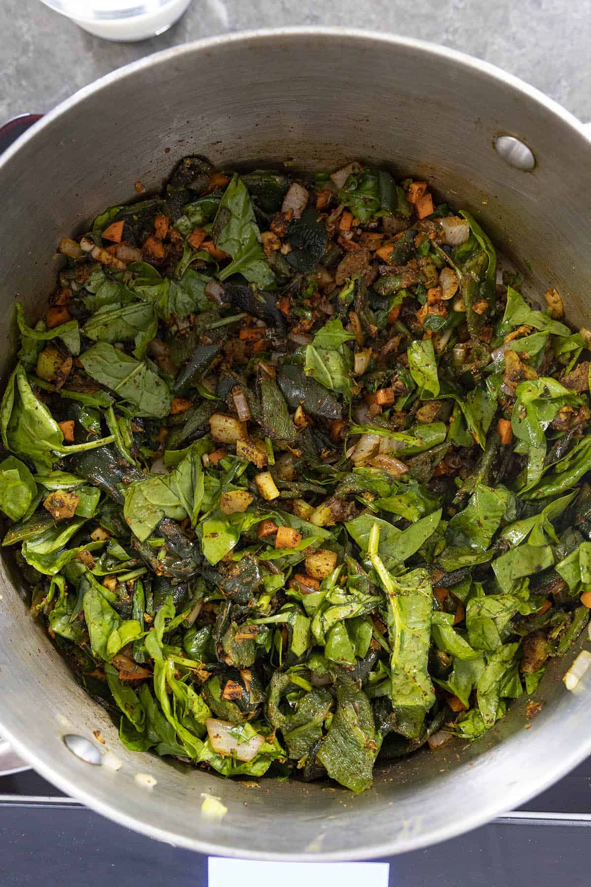 Cooking down the spinach and vegetables to make Roasted Poblano Soup