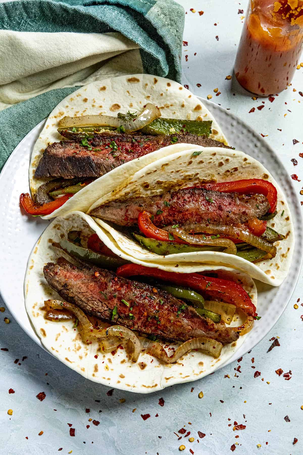 Three Steak Fajitas on a plate with hot sauce