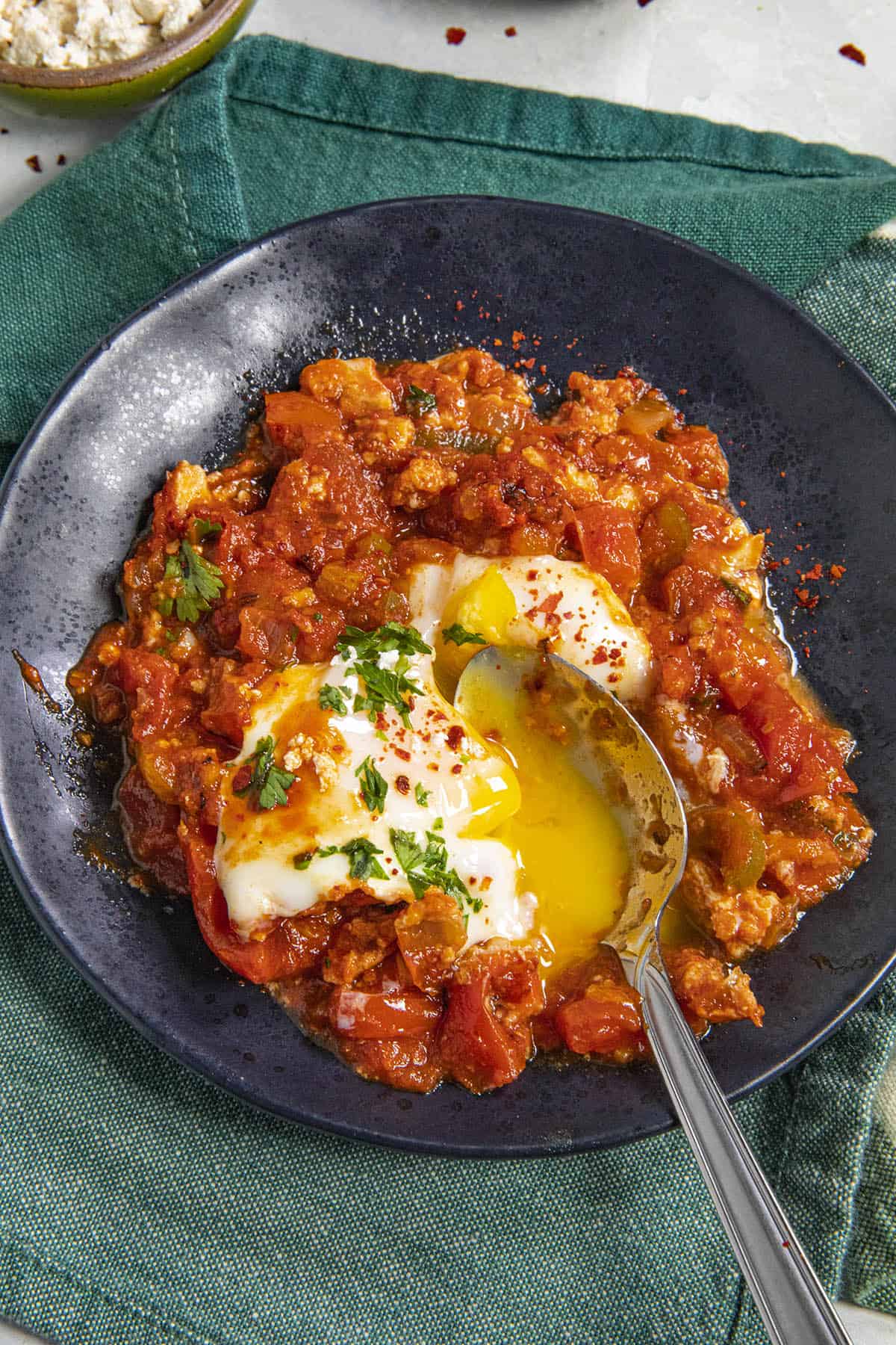 Mike taking a spoonful of Shakshuka, with runny egg yolk