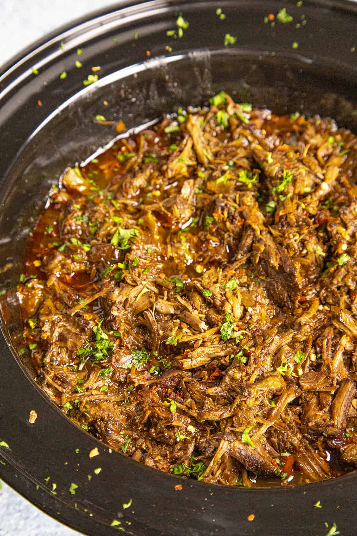 Beef Barbacoa in a slow cooker with garnish