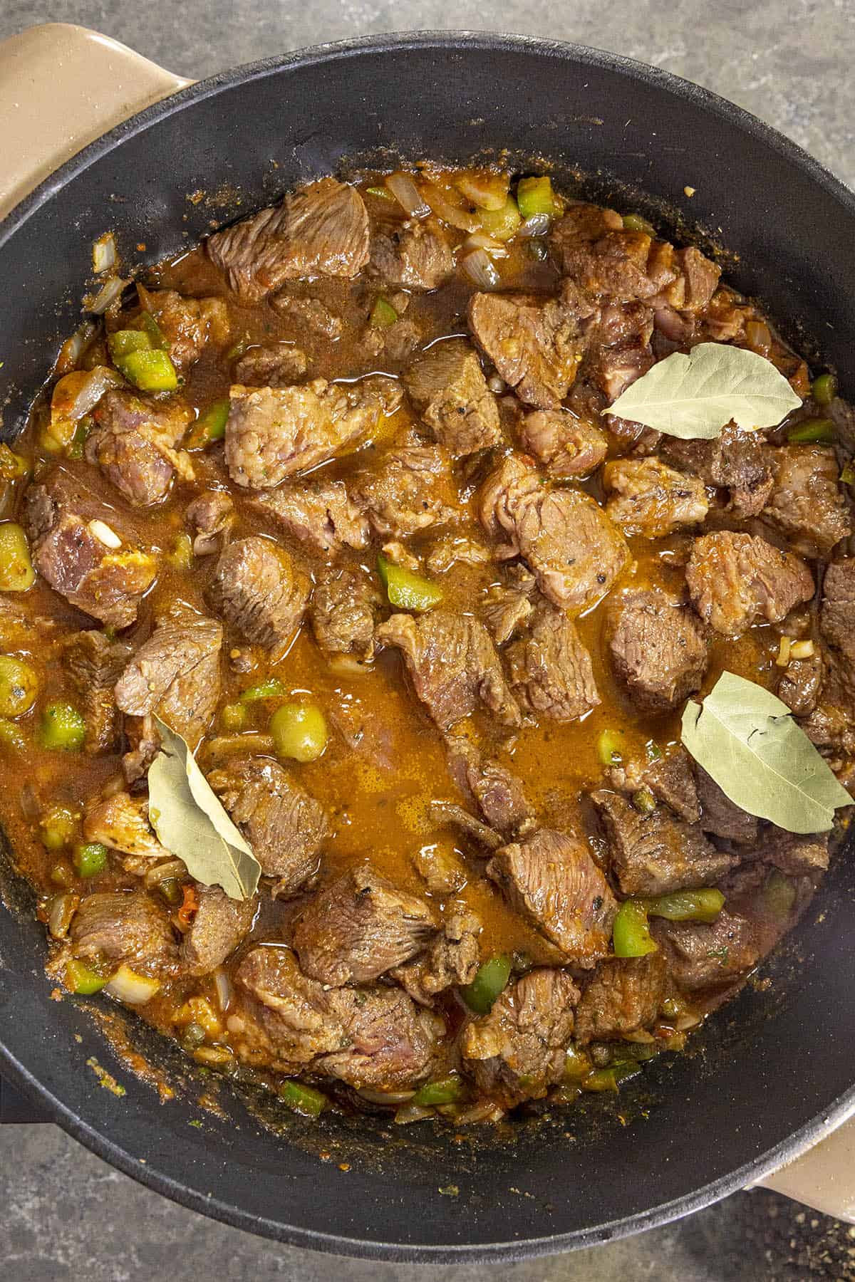 Carne Guisada beef simmering in a pan