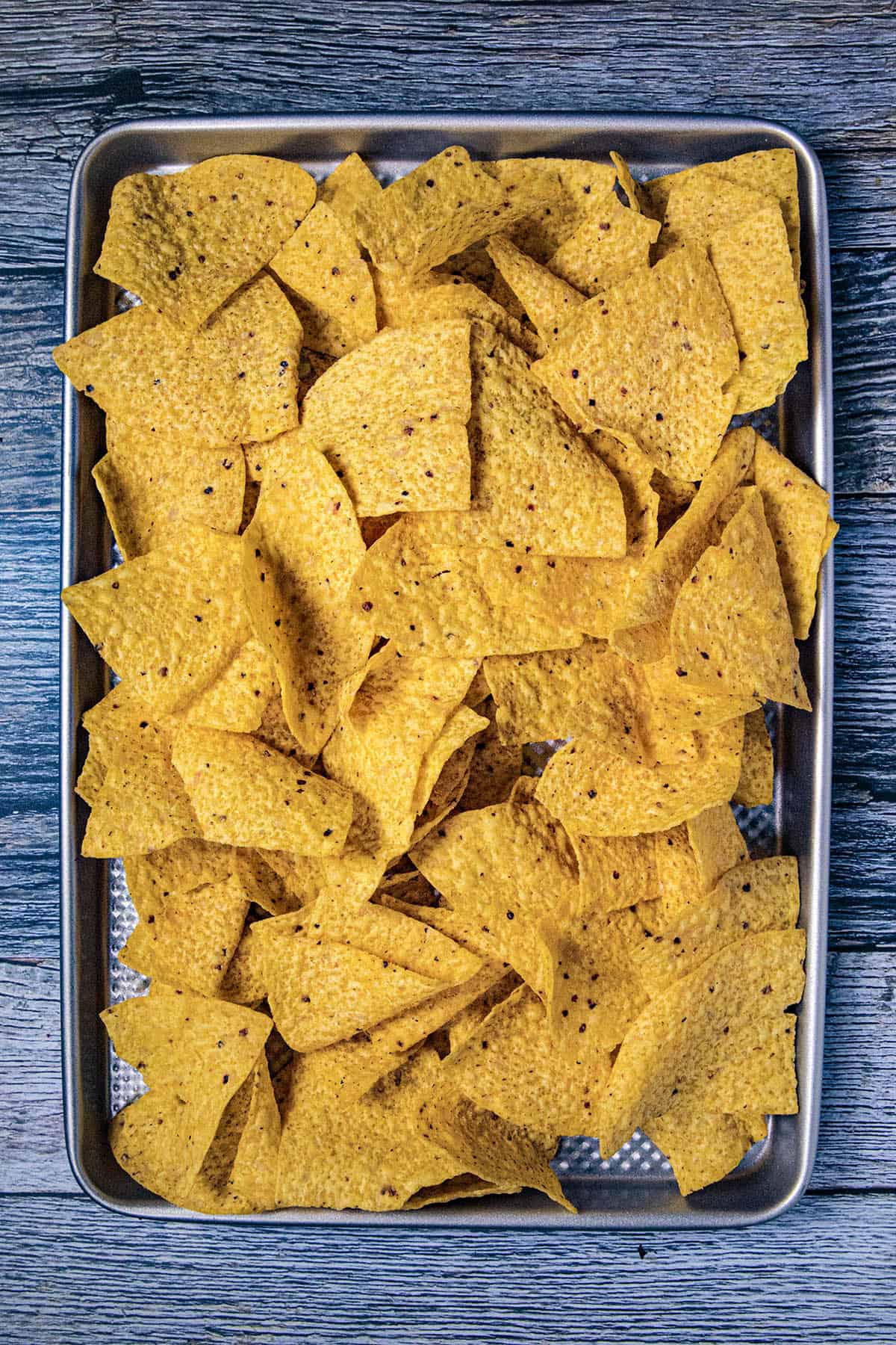 Layering crunchy tortilla chips on a baking pan for making nachos