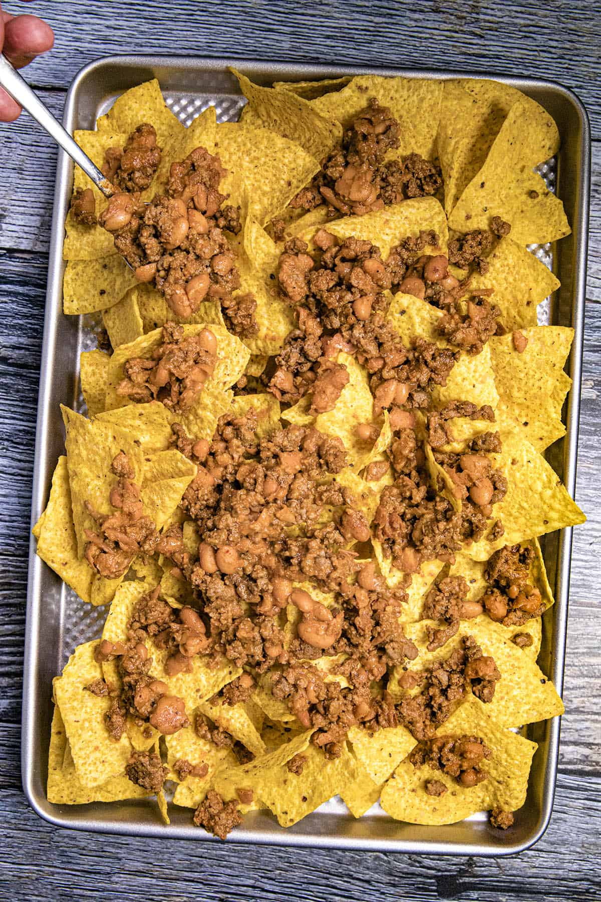 Layering the nacho chips with the taco meat and bean mixture