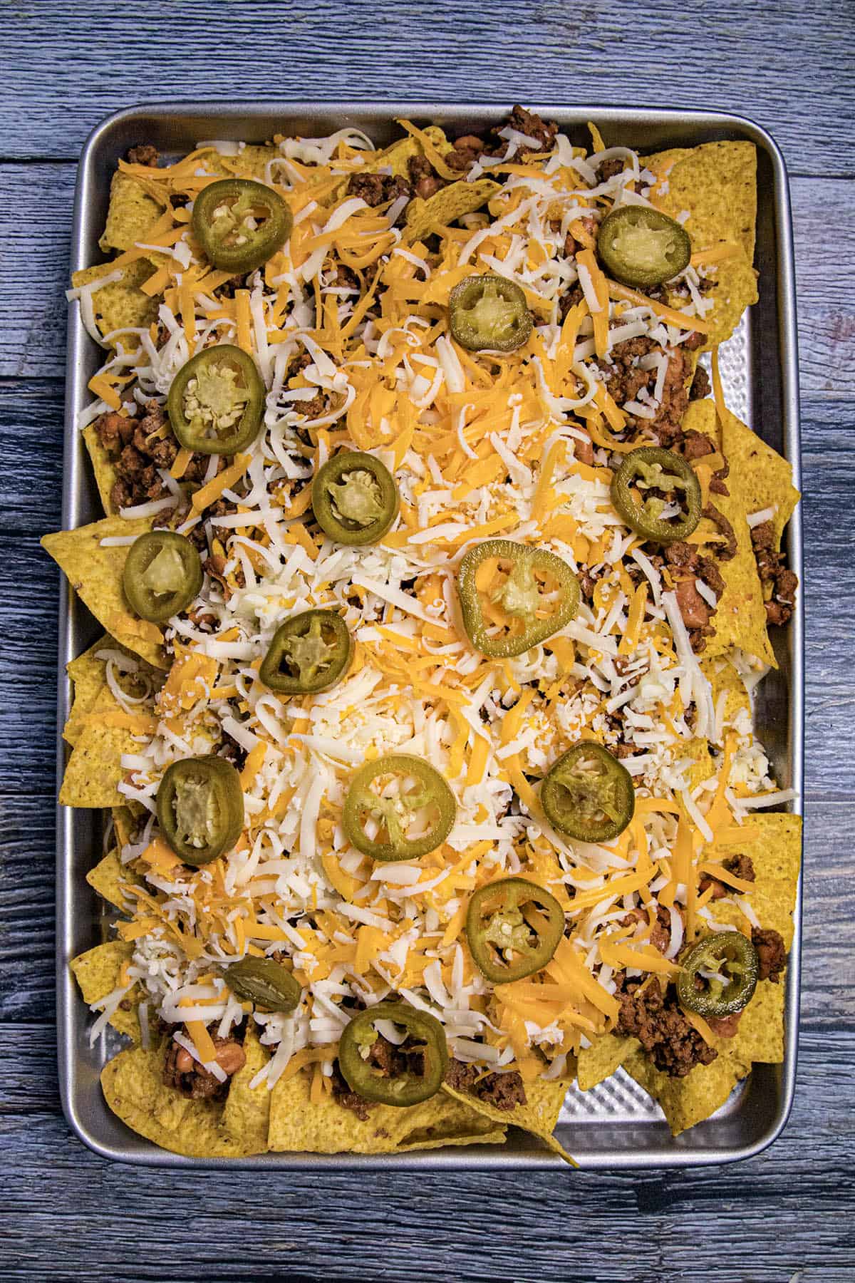 Topping the nachos with pickled jalapenos
