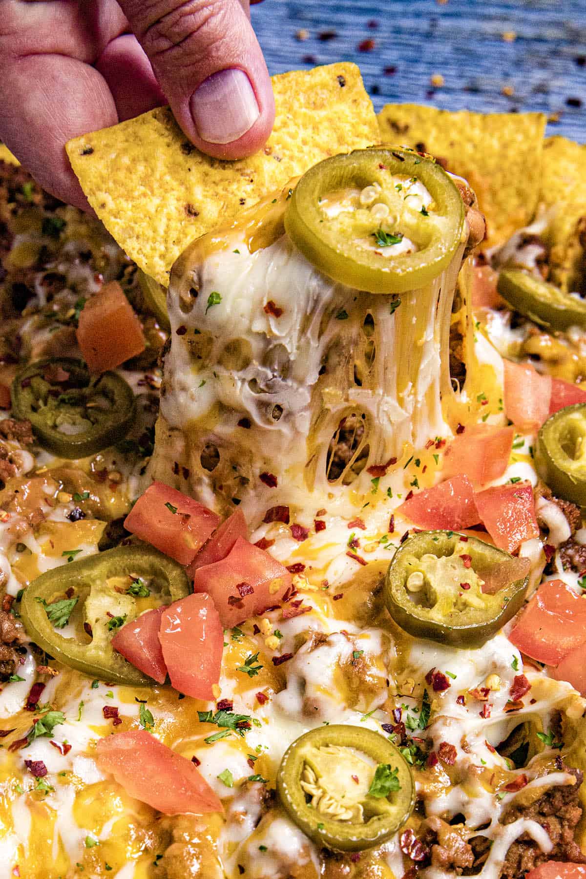 A nacho chip with lots of gooey cheese