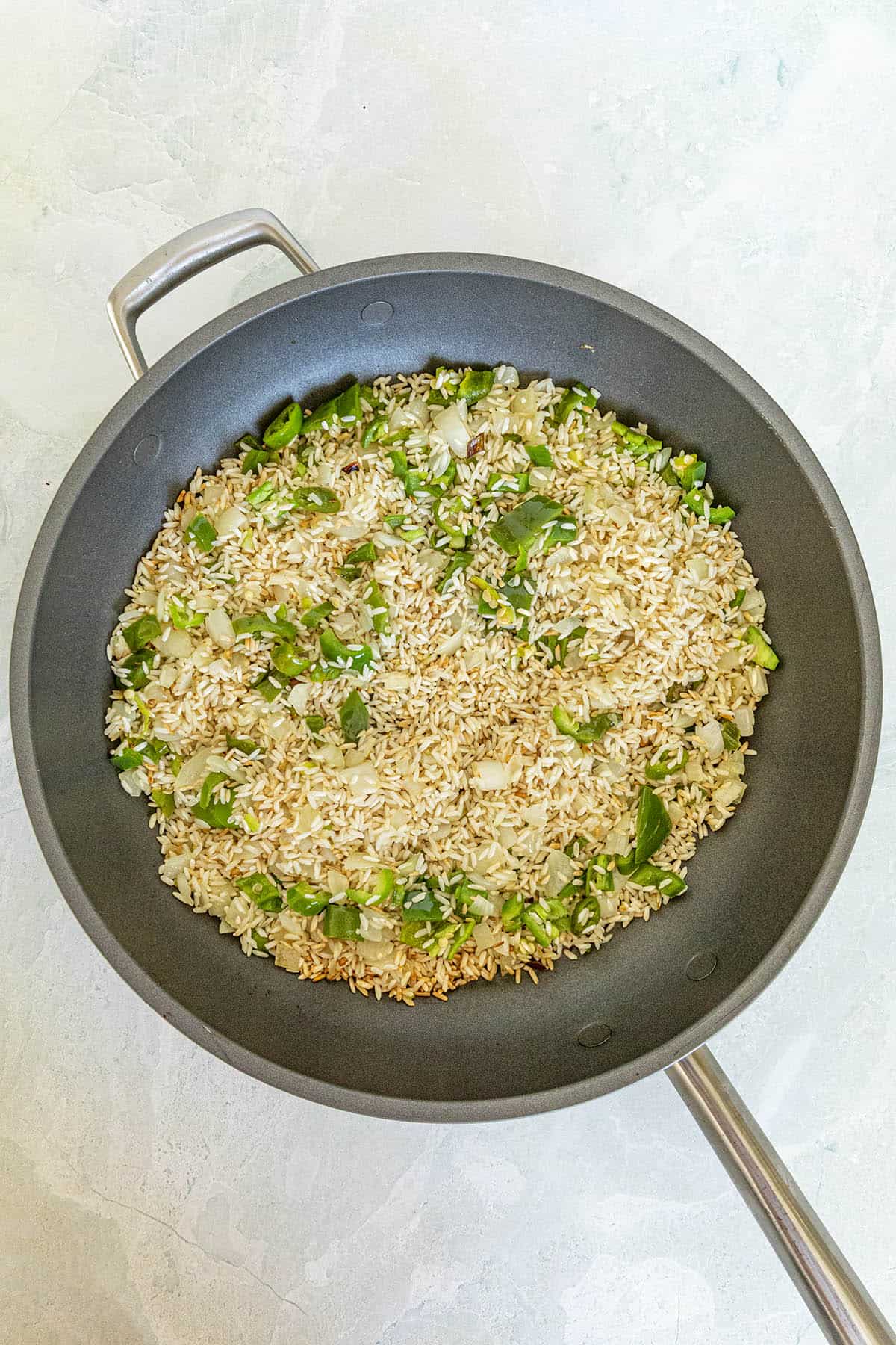 Cooking vegetables and toasting rice to make Yellow Rice