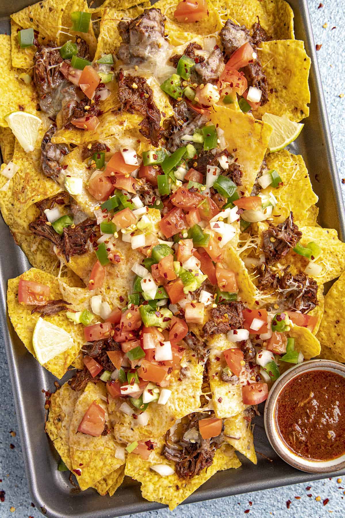 Birria Nachos on a serving platter with lots of garnish