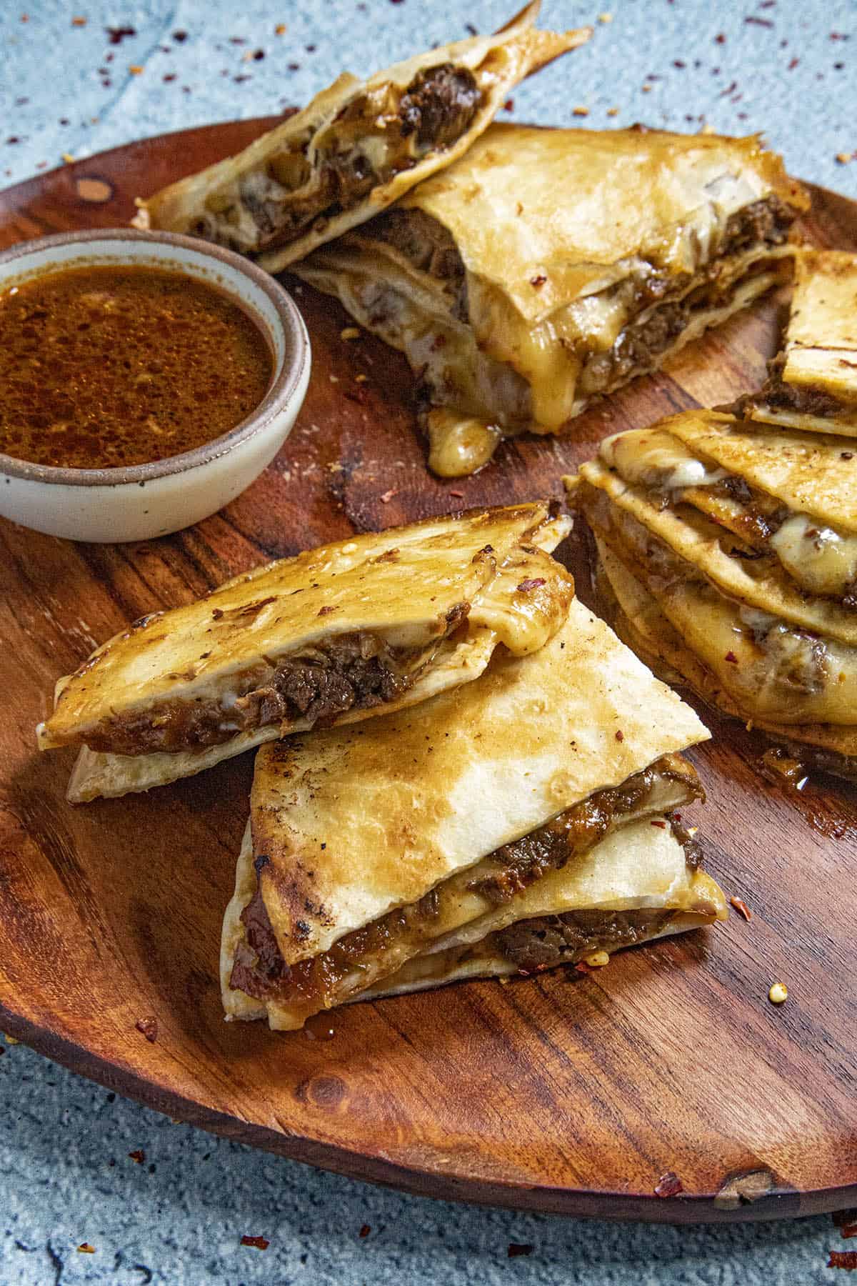 Fresh Birria Quesadillas on a platter for serving, with sauce on the side