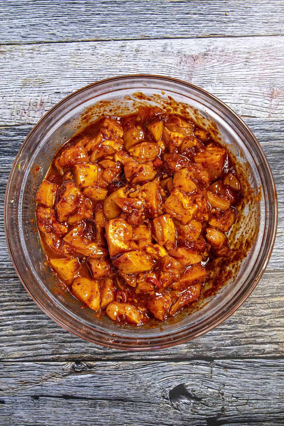 Pieces of chicken marinating in a fiery sauce