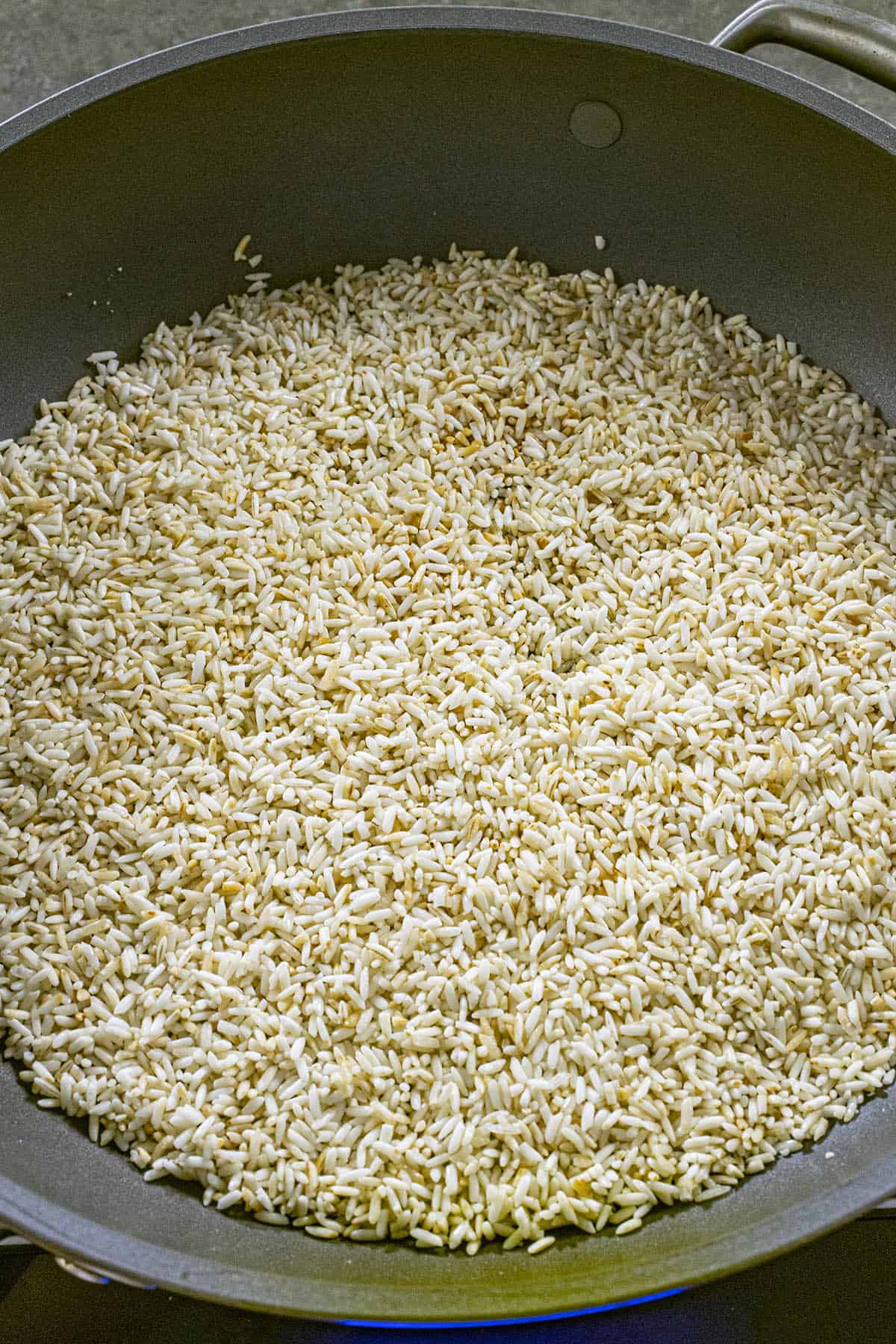 Browning the rice in a pan to make Mexican rice