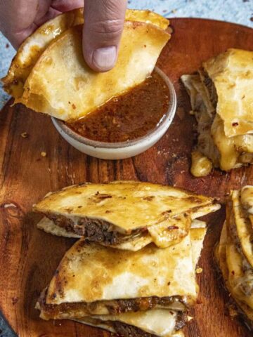 Dipping a Birria Quesadilla into the birria consome