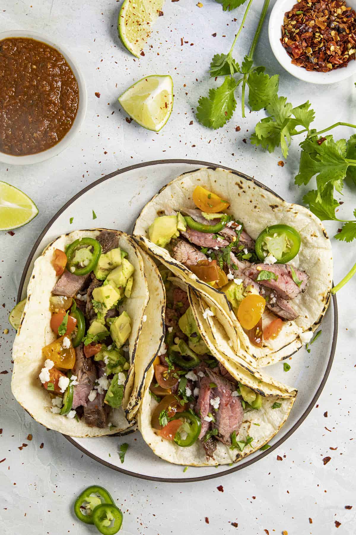 A plate of Carne Asada Tacos with lots of fixings to choose from