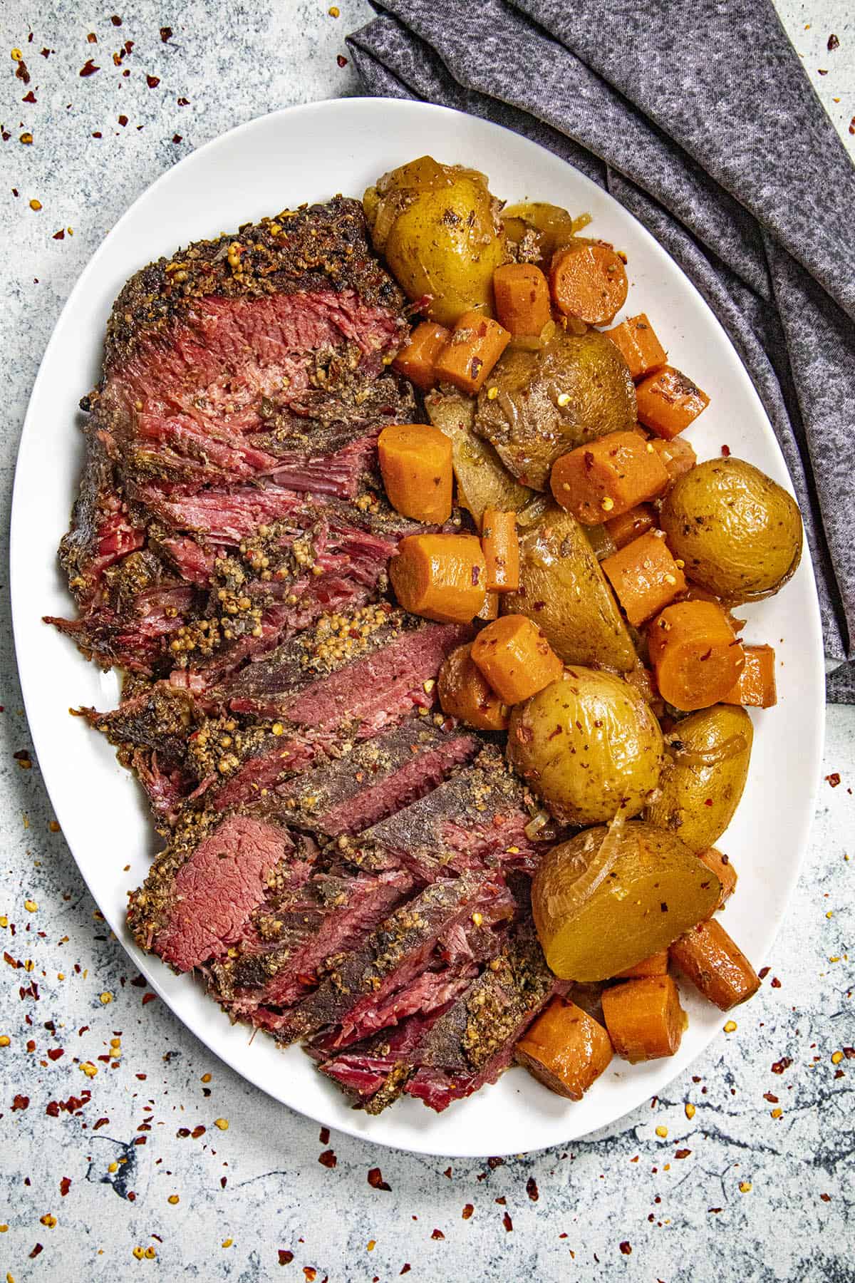 Sliced corned beef on a platter with potatoes and carrots