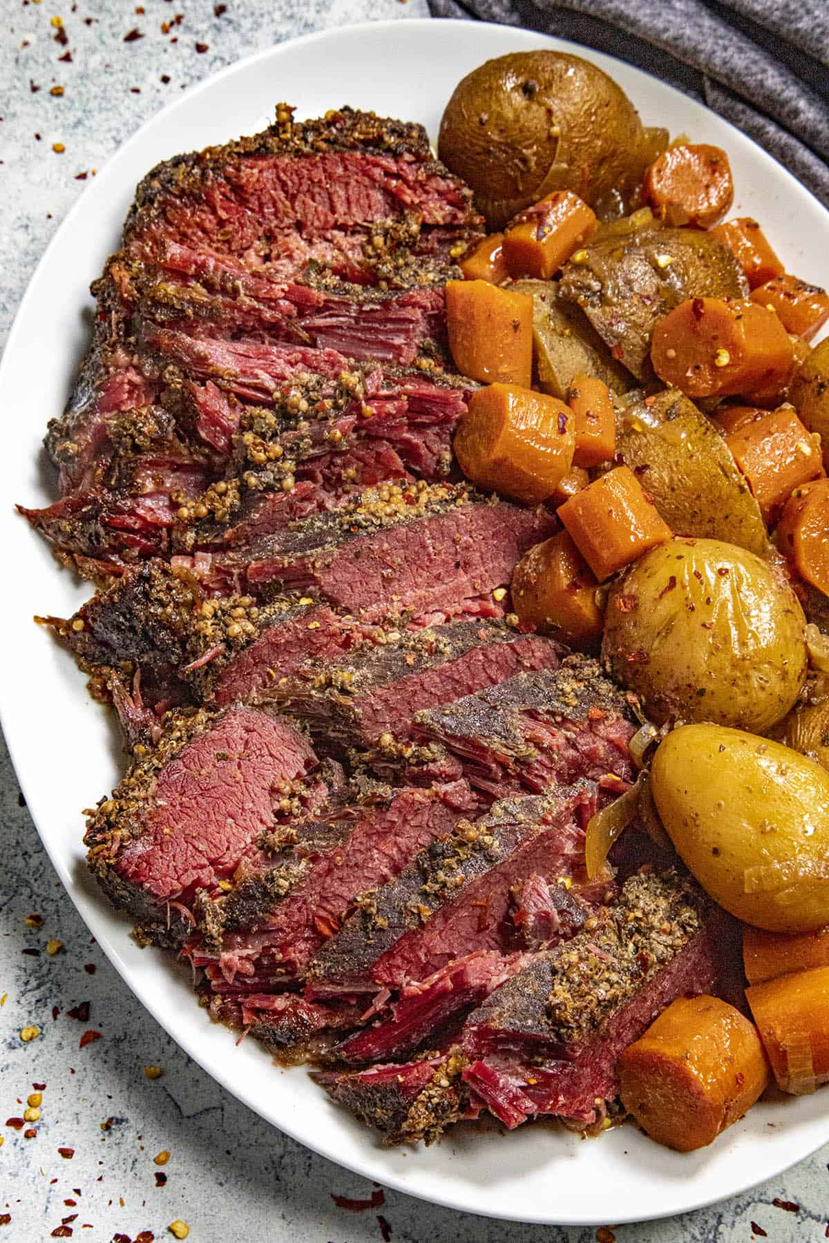 Fall apart tender crock pot corned beef on a platter with slow cooked carrots and potatoes