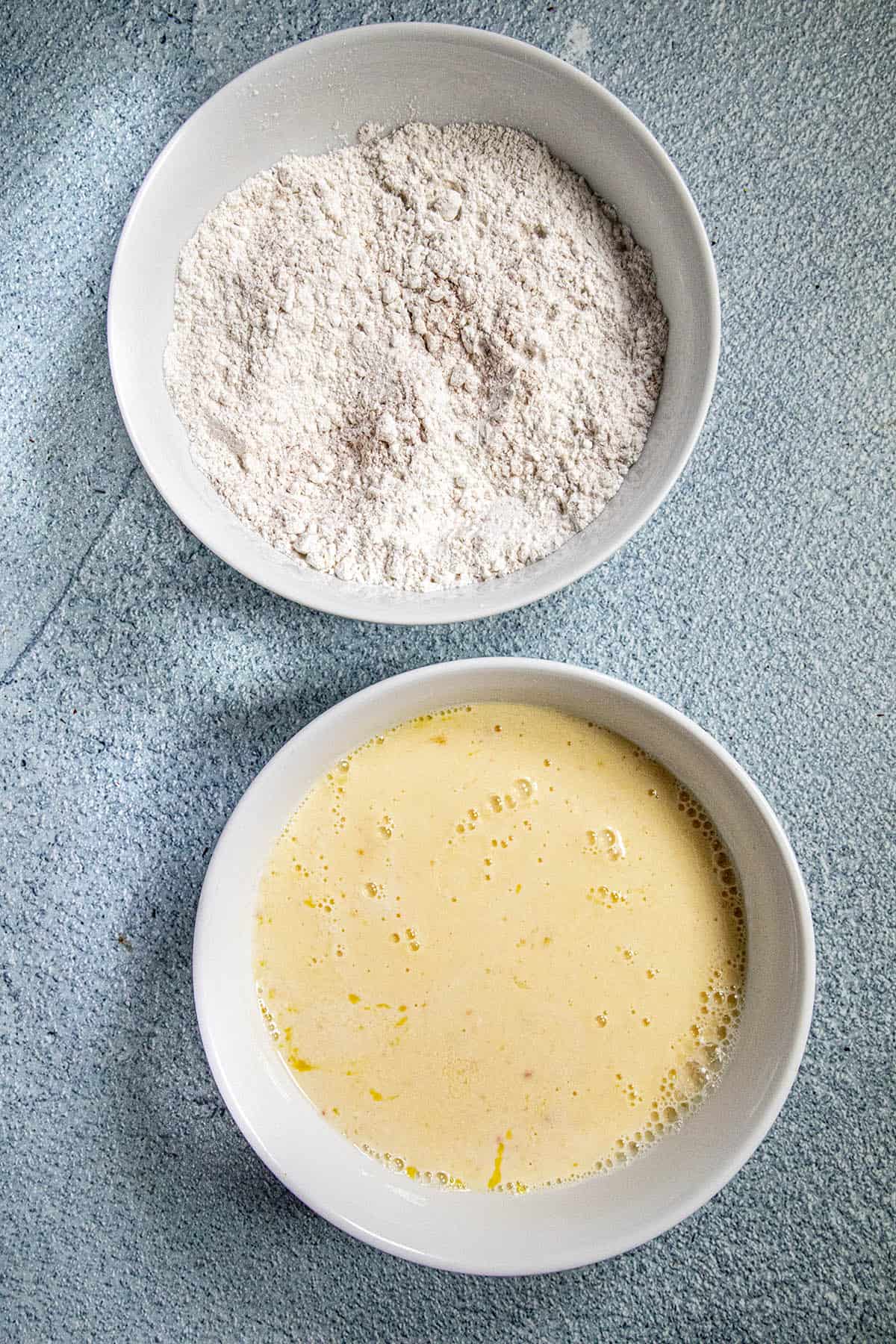 The breading station to make Fried Chicken Wings, 2 bowls, one with a flour mix, one with beaten eggs mixture