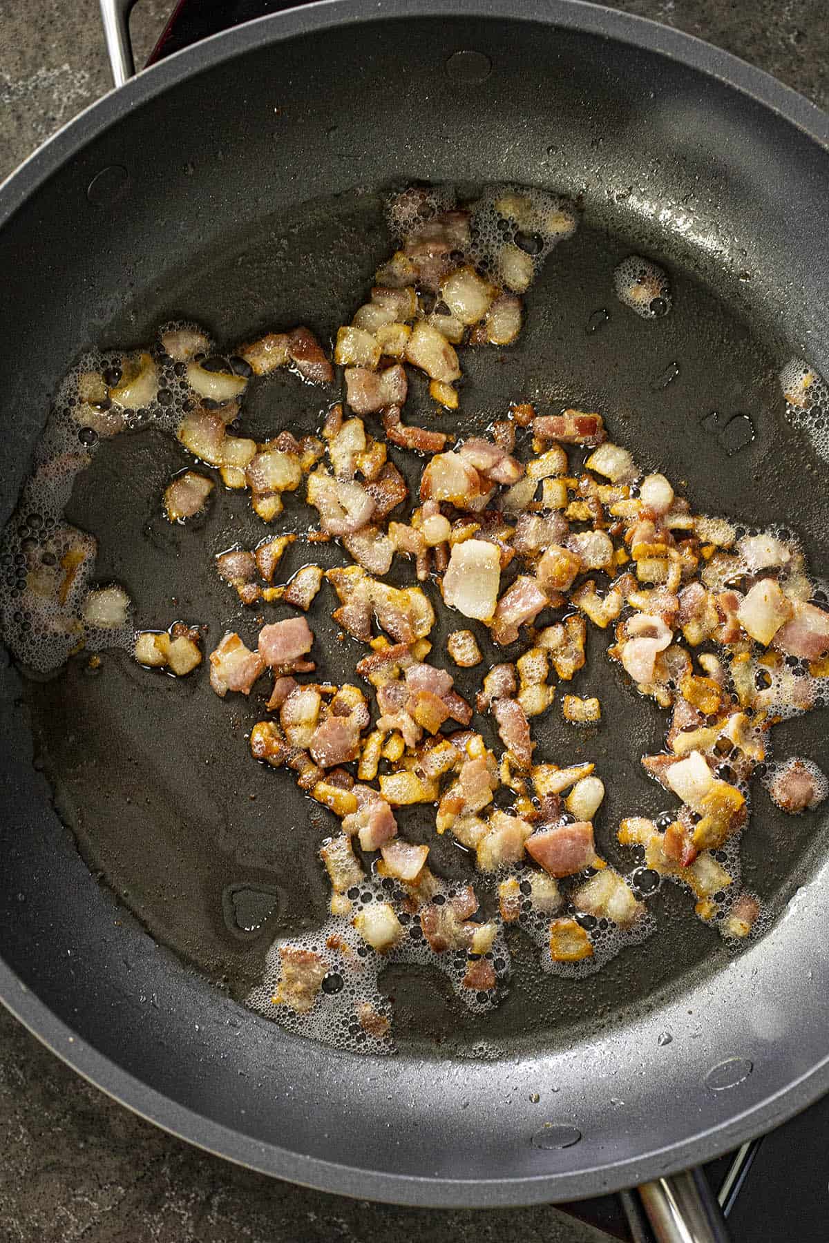 Cooking bacon in a pan to make Corn Maque Choux