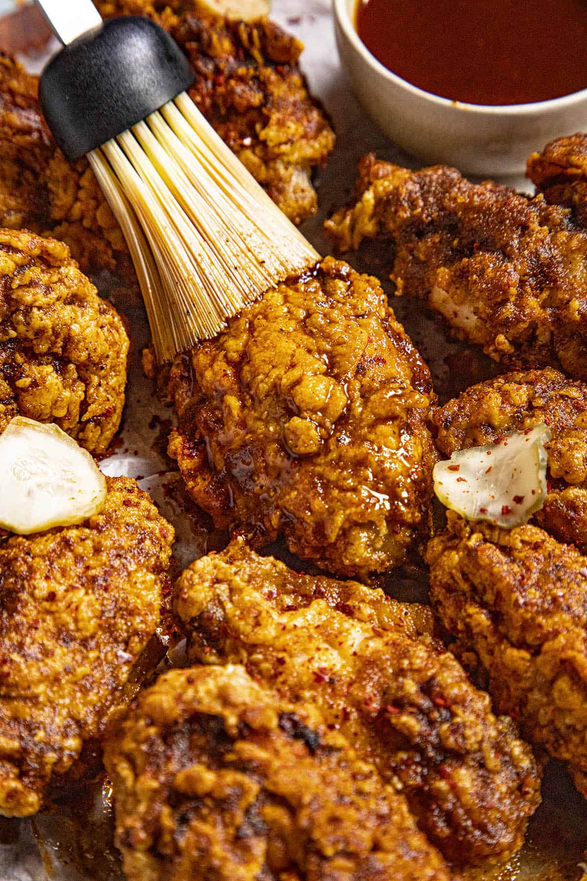 Brushing the fried chicken wings with extra Nashville hot sauce