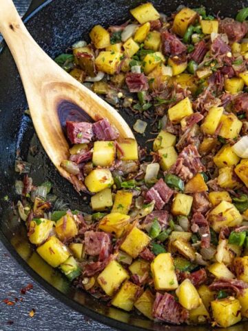 Scooping a serving of Corned Beef Hash from the hot pan