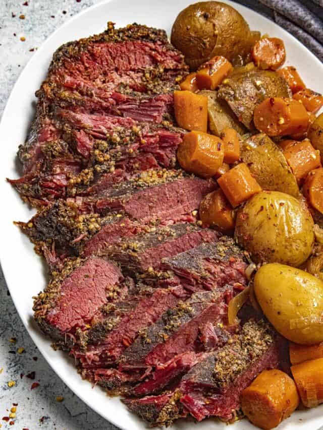 Fall apart tender crock pot corned beef on a platter with slow cooked carrots and potatoes