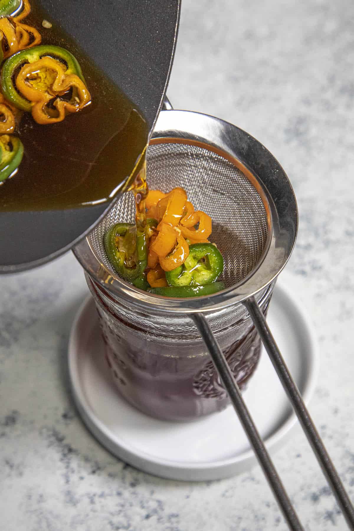 Straining hot honey into a jar