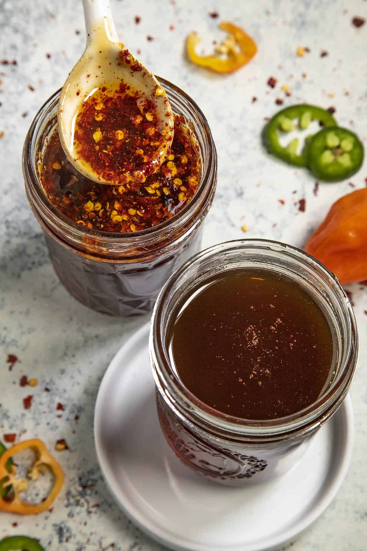 Hot honey in a jar with chili flakes next to a jar of strained hot honey