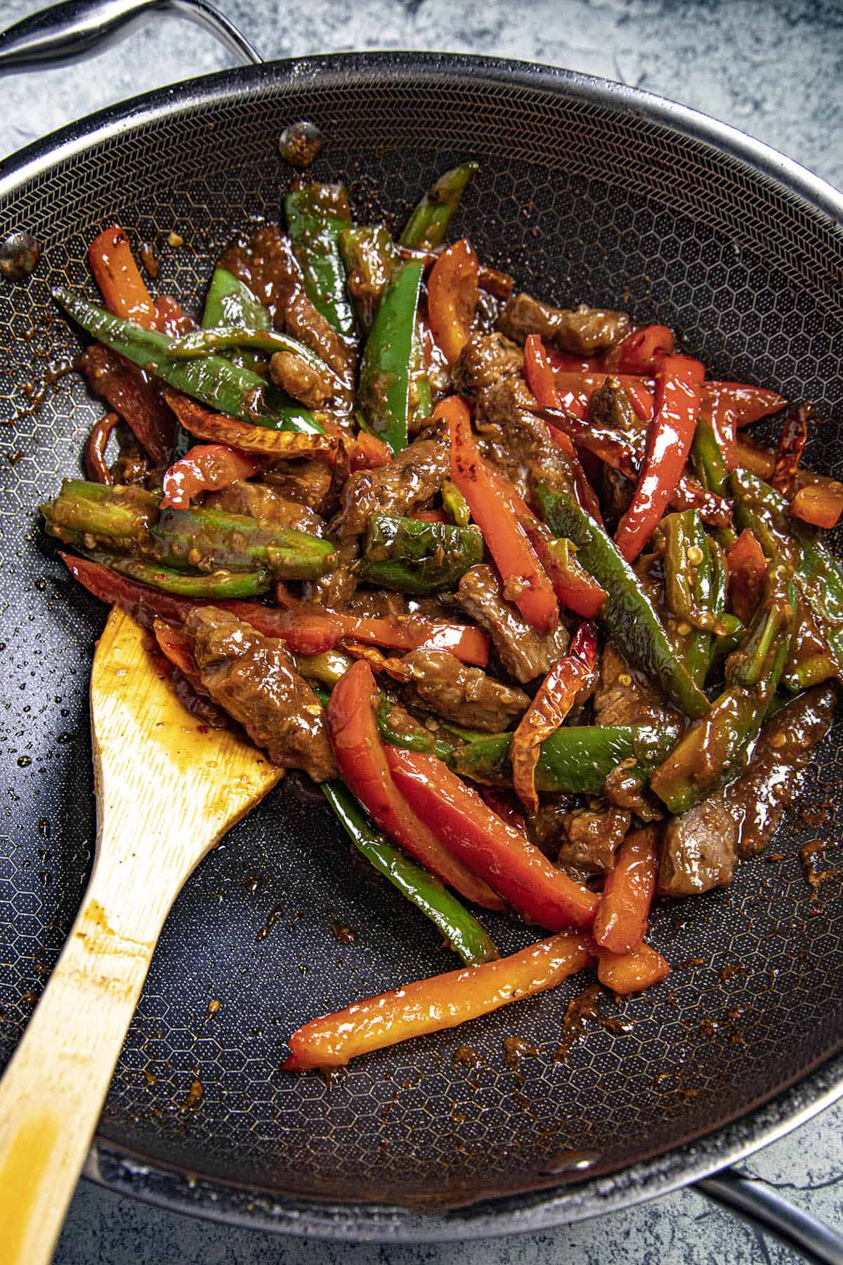 Stirring the spicy sauce into the Hunan Beef and vegetables