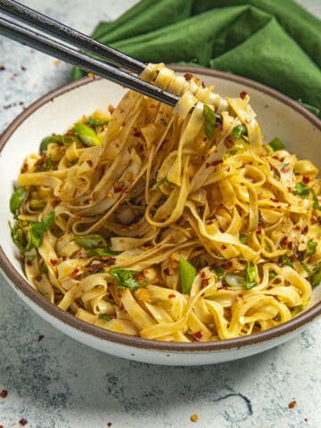 Mike taking chili oil noodles from the bowl with chopsticks