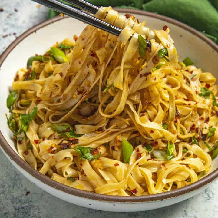 Mike taking chili oil noodles from the bowl with chopsticks