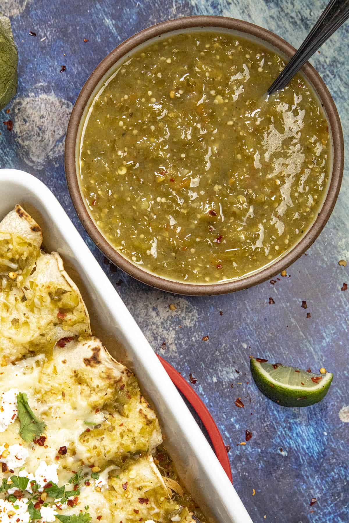 Green Enchilada Sauce in a bowl with enchiladas verdes in a pan