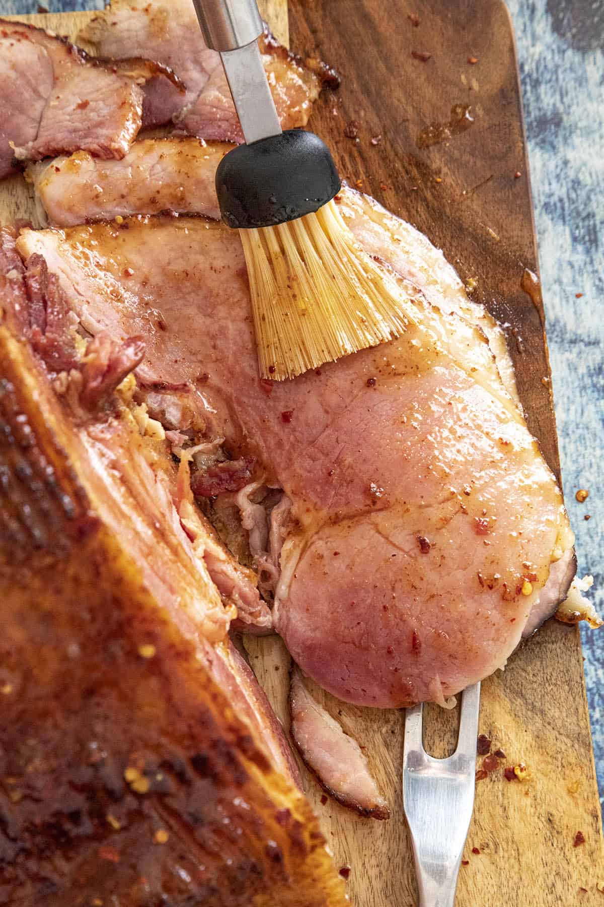 Glazing slices of baked spiral ham with hot honey