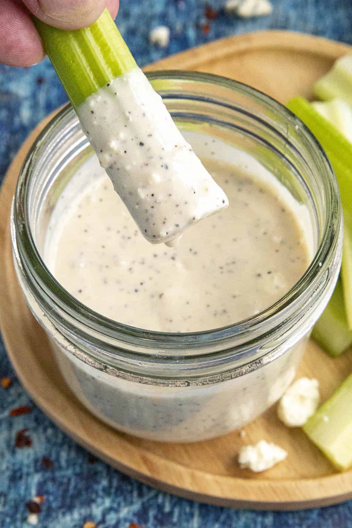 Dipping a celery stalk into Creamy Blue Cheese Dressing