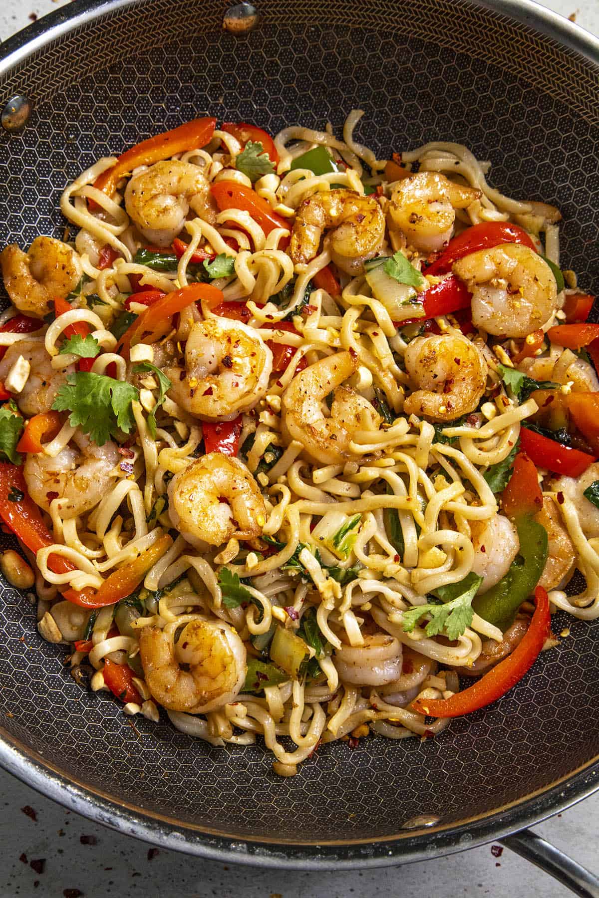 Spicy Thai Noodles in a wok with lots of peppers and shrimp