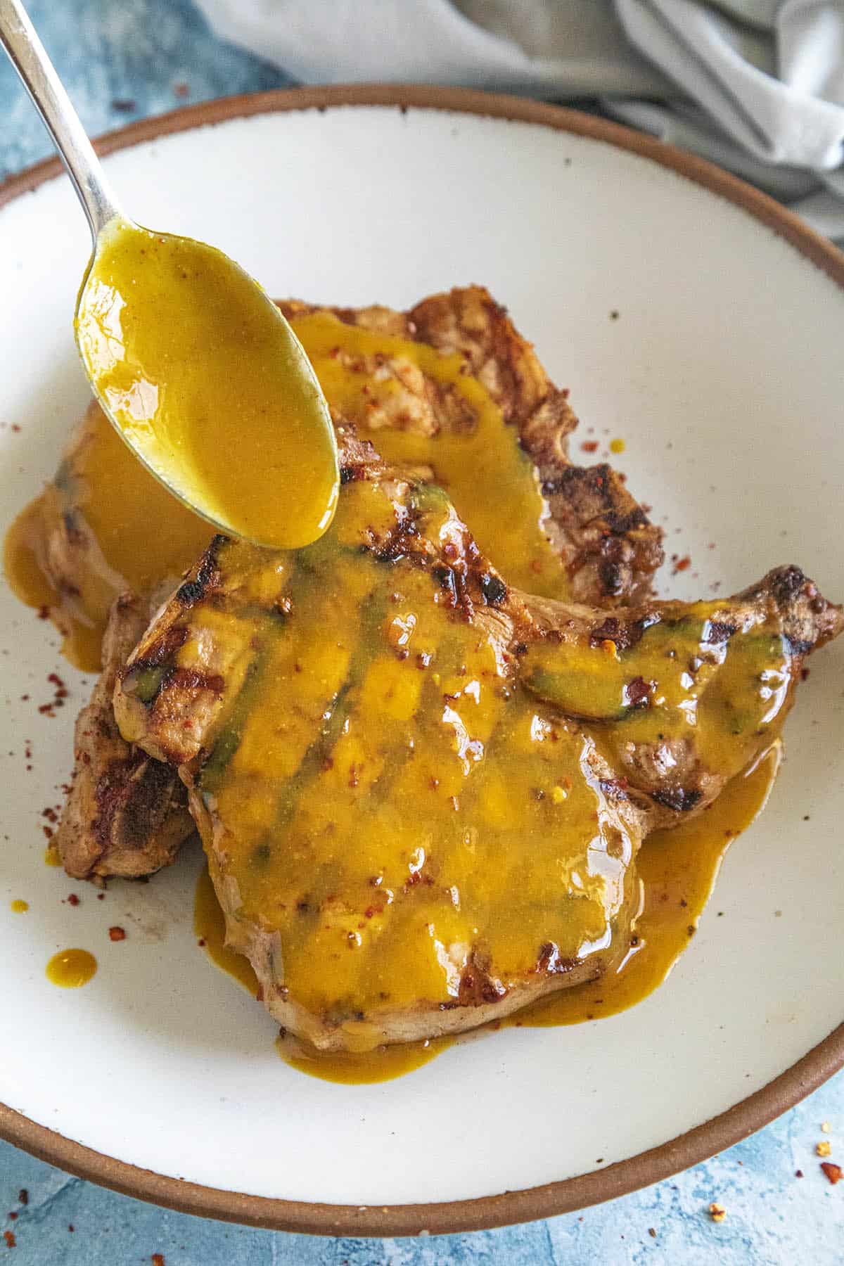 Spooning Carolina Gold Mustard BBQ Sauce over Grilled Pork Chops