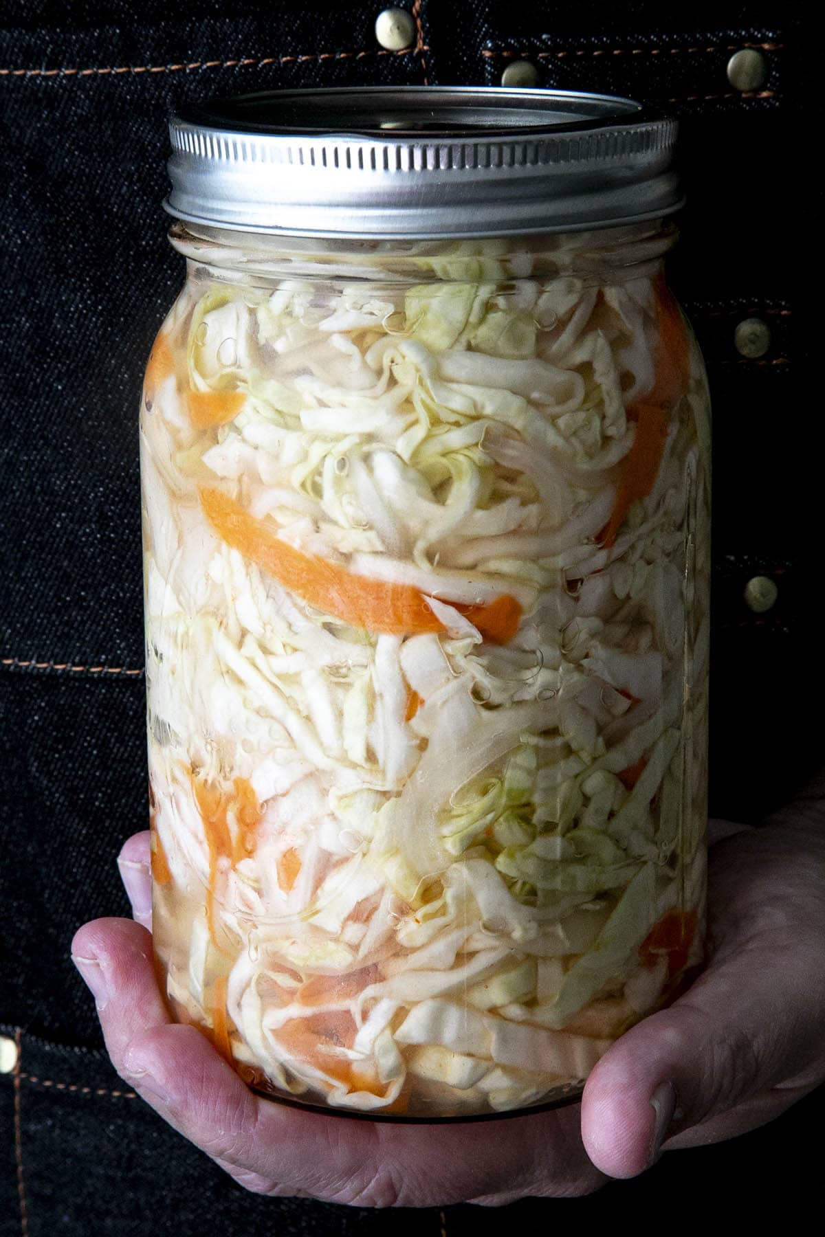 Mike holding a filled jar of Curtido (Salvadoran Cabbage Slaw)
