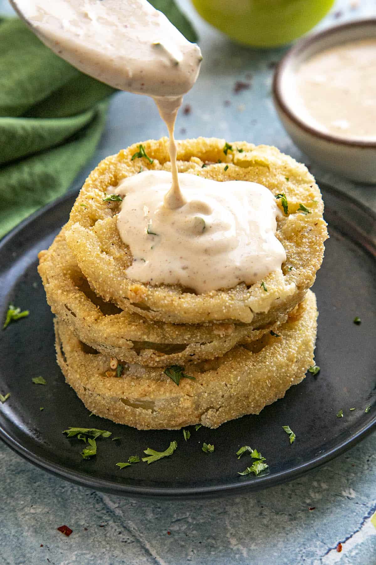 Drizzling creamy remoulade over Fried Green Tomatoes